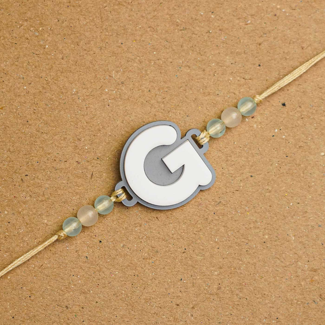 Personalized Handmade 3D Alphabet Acrylic Rakhi With Roli Chawal - Letter G Close-up on Surface