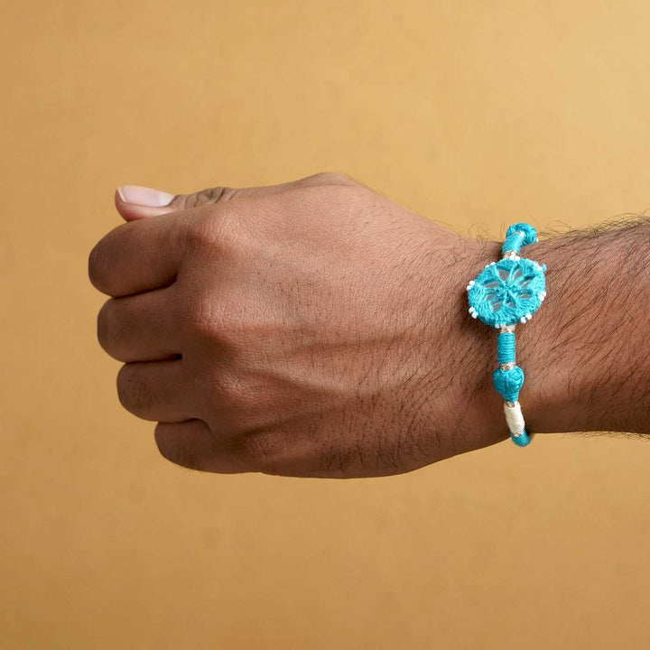 Handmade Mirror Work Patwa Turquoise Blue Pink Cotton Rakhi With Roli Chawal Set Of 2 - Blue Rakhi on wrist close-up