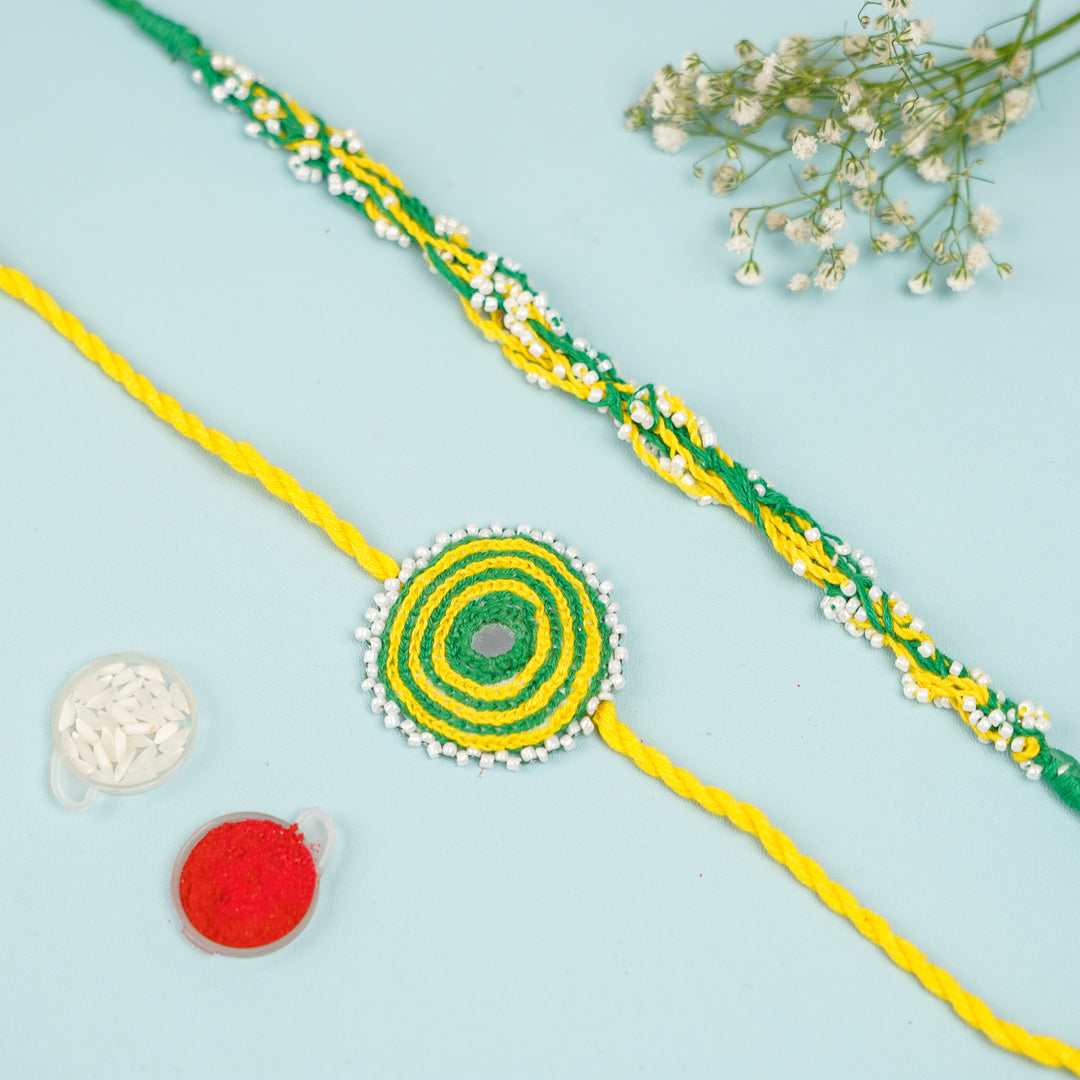 Handmade Reusable Yellow And Green Mirror And Jhumki Cotton Rope Rakhi For Bhaiya And Bhabhi - Flat Lay with Accessories