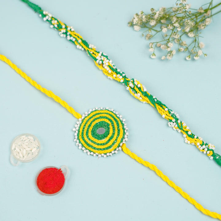 Handmade Reusable Yellow And Green Mirror And Jhumki Cotton Rope Rakhi For Bhaiya And Bhabhi - Flat Lay with Accessories