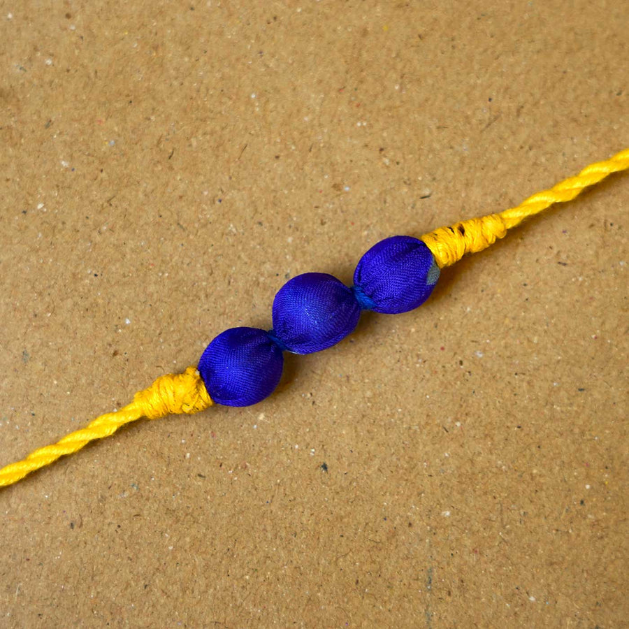 Handmade Bright Yellow Upcycled Fabric Rakhi With Roli Chawal - Close-up of single rakhi detail