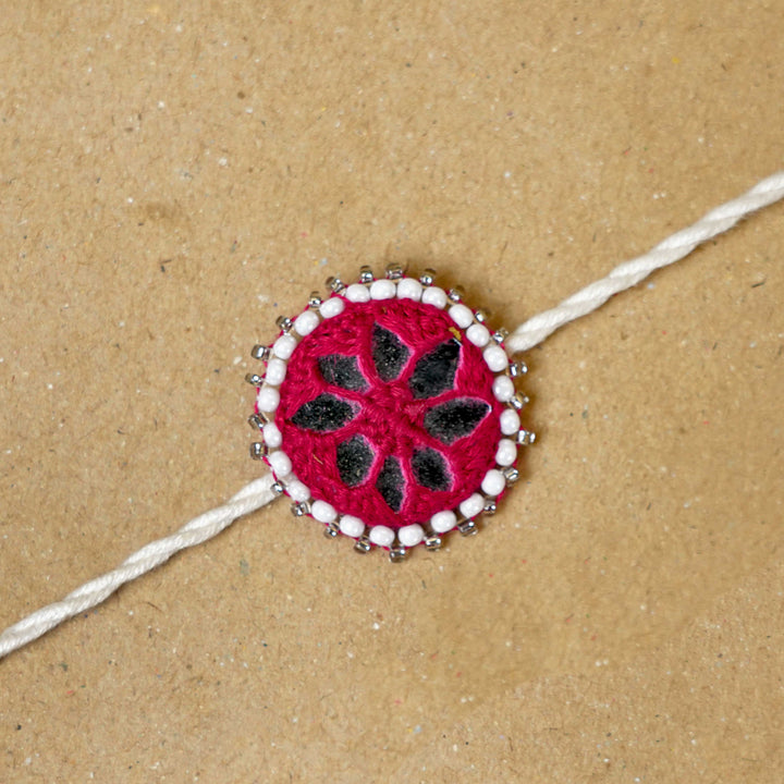 Handmade Mirror Work Kajal Maroon White Cotton Rakhi With Roli Chawal - Close-up of Rakhi centerpiece