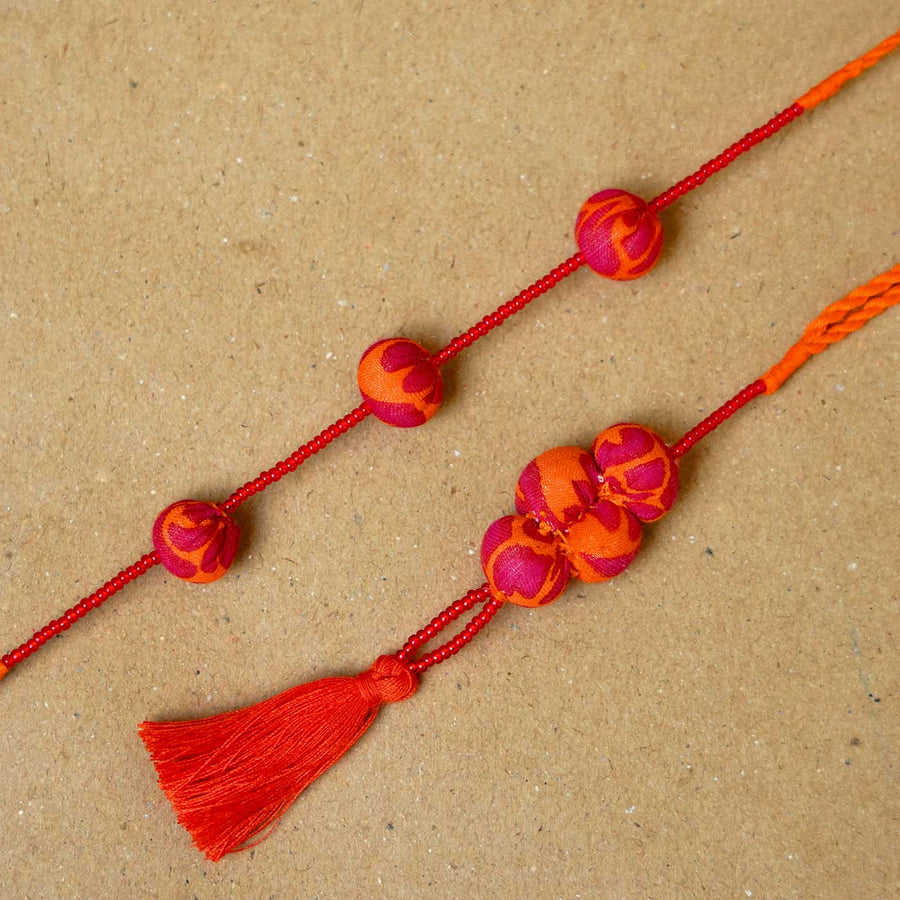 Handmade Kesari Potli Upcycled Fabric Bhaiya Bhabhi Rakhi With Roli Chawal Set Of 2 - Close-up of bead and tassel details