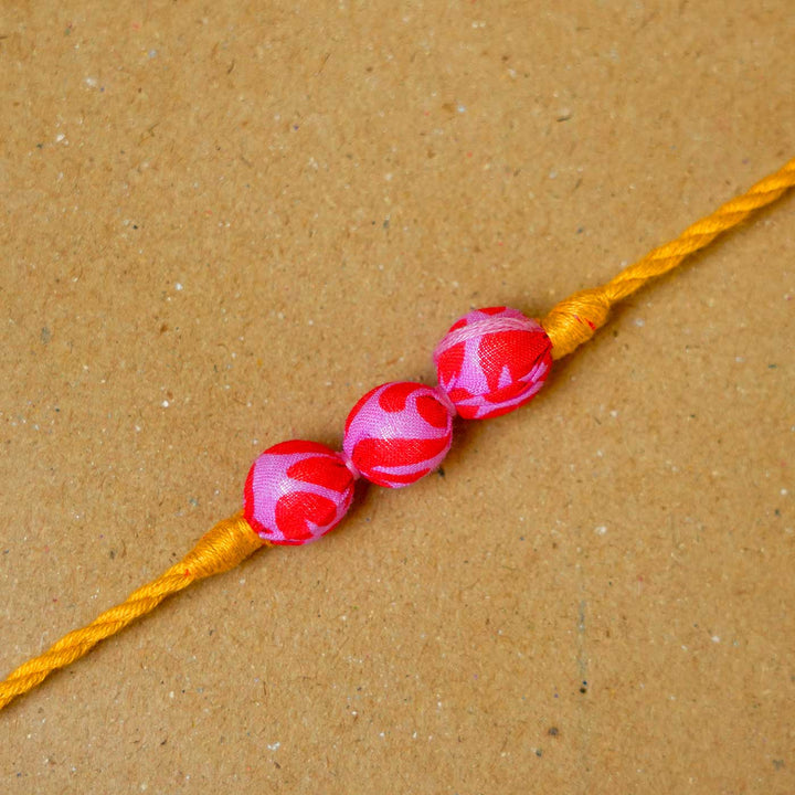 Handmade Ochre Upcycled Fabric Rakhi With Roli Chawal - Close-up of central beads