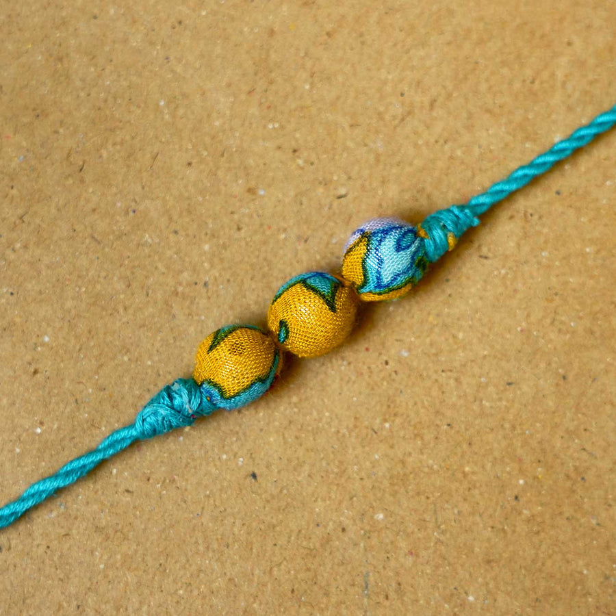 Handmade Turquoise Upcycled Fabric Rakhi With Roli Chawal - Close-up of Beaded Thread