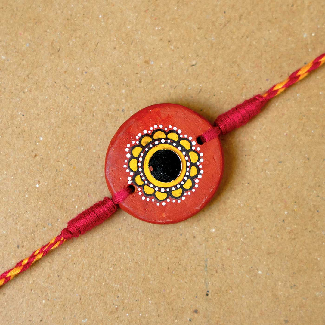 Hand Painted Suraj Terracotta Rakhi With Roli Chawal - Close-up of Rakhi centerpiece