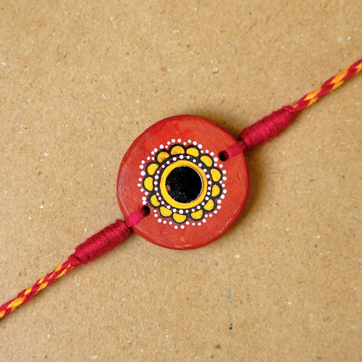 Hand Painted Suraj Terracotta Rakhi With Roli Chawal - Close-up of Rakhi centerpiece