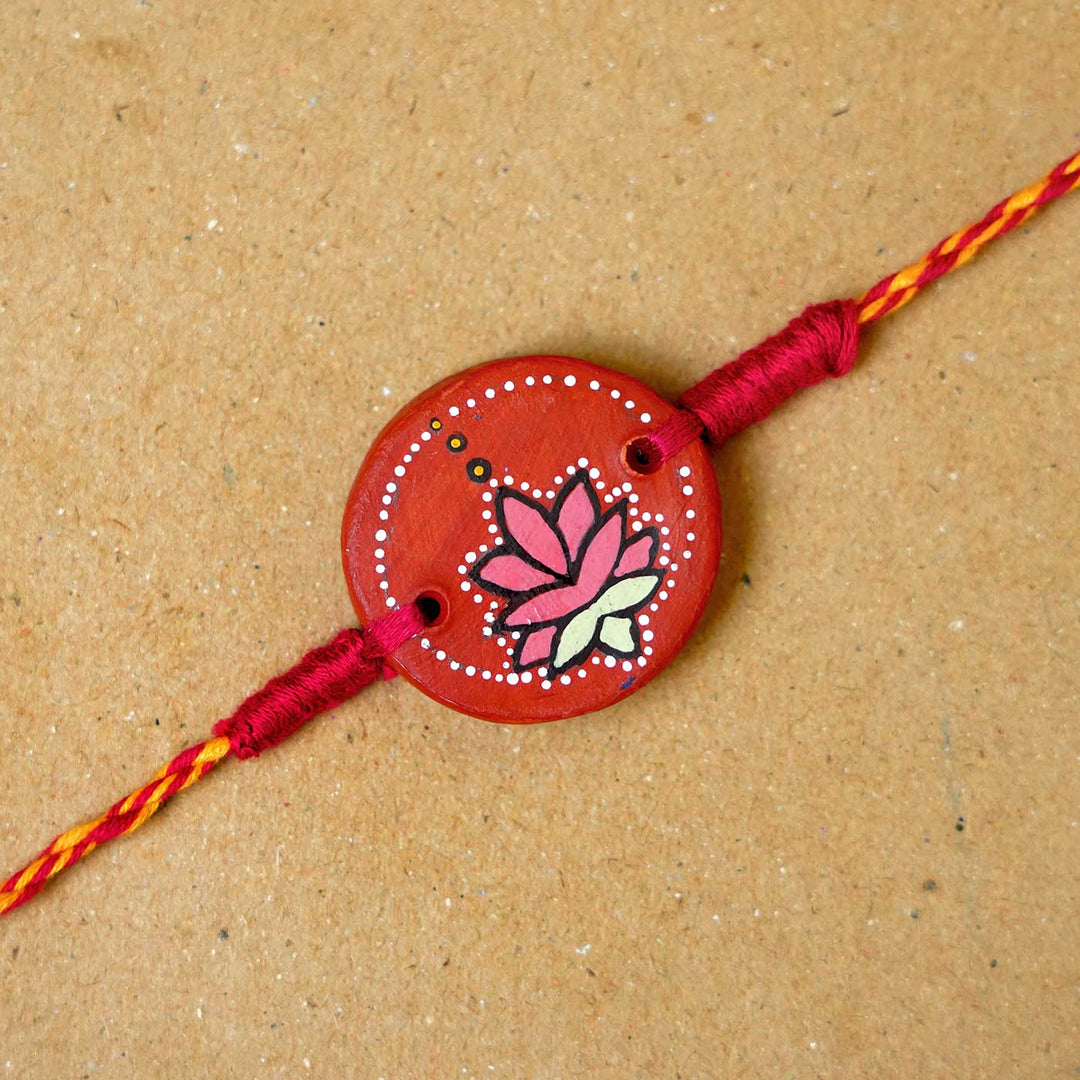 Hand Painted Kamal Terracotta Rakhi With Roli Chawal - Close-up of bracelet centerpiece