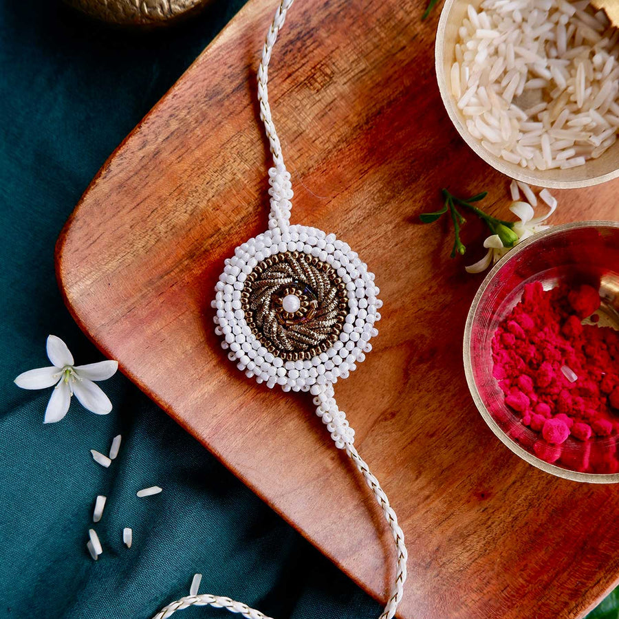 Handmade Zardozi White Bead Border Rakhi With Wooden Box And Roli Chawal - Front View with Ritual Items