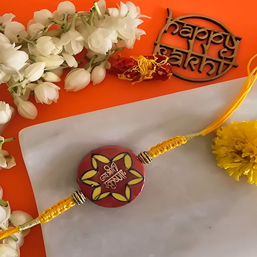 Handmade Laser Cut Red Jai Shree Krishna Ceramic Rakhi With Roli Chawal For Brother - Close-up of central rakhi design