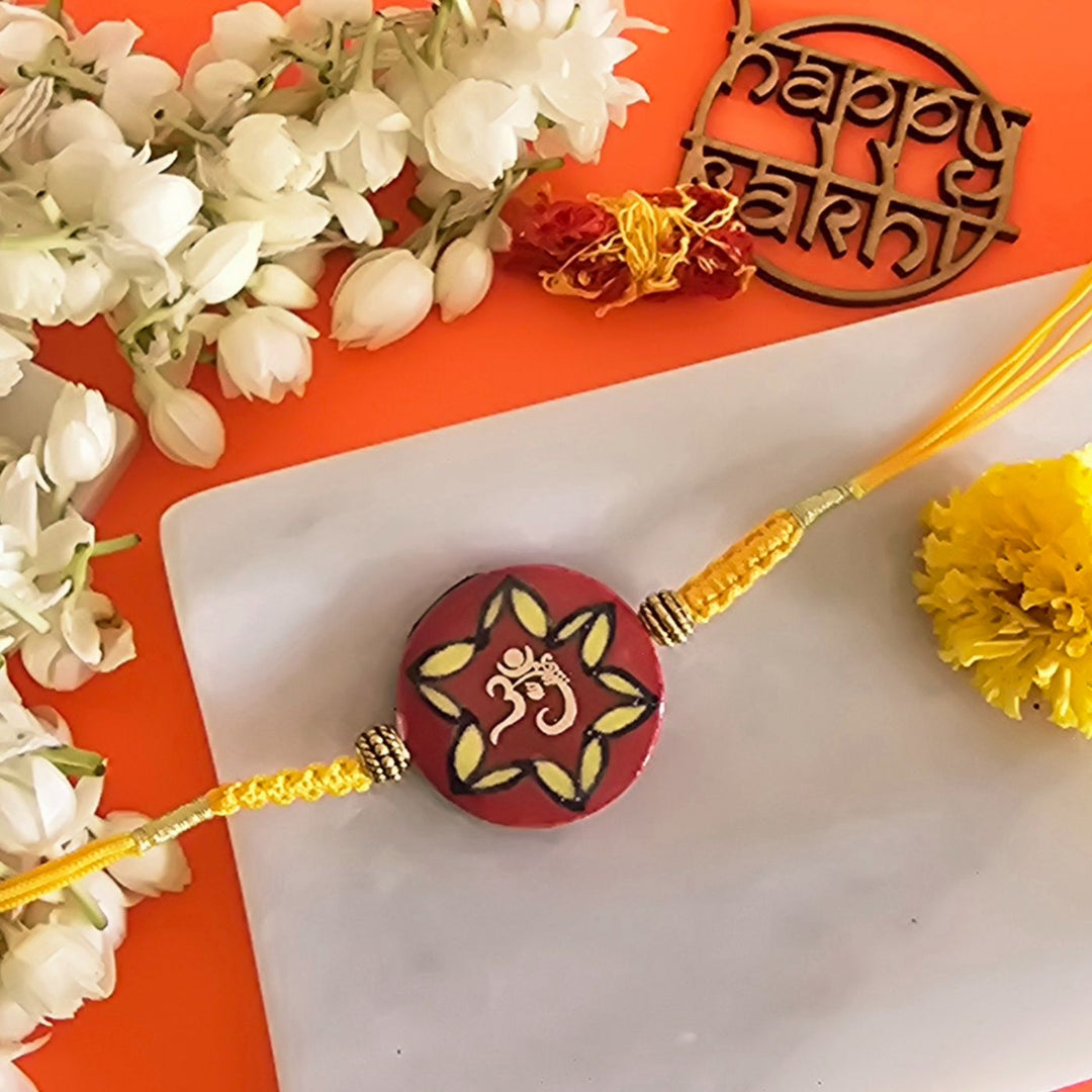 Handmade Laser Cut Red Om Ceramic Rakhi With Roli Chawal For Brother - Close-up of Rakhi Threaded Piece