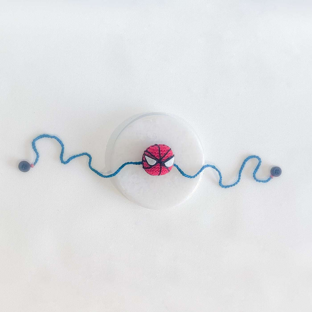 Handmade Crochet Spiderman Kids Rakhi With Roli Chawal - Flat Lay with Marble Base
