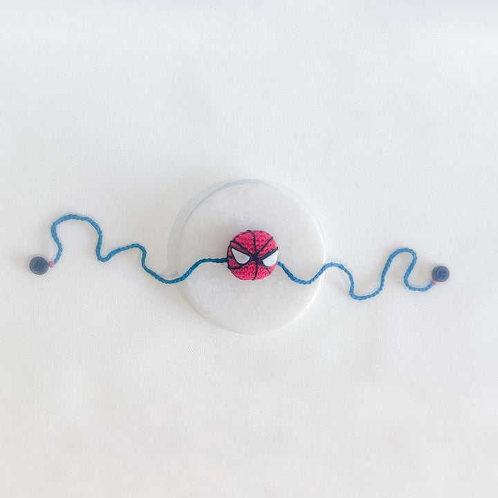 Handmade Crochet Spiderman Kids Rakhi With Roli Chawal - Flat Lay with Marble Base