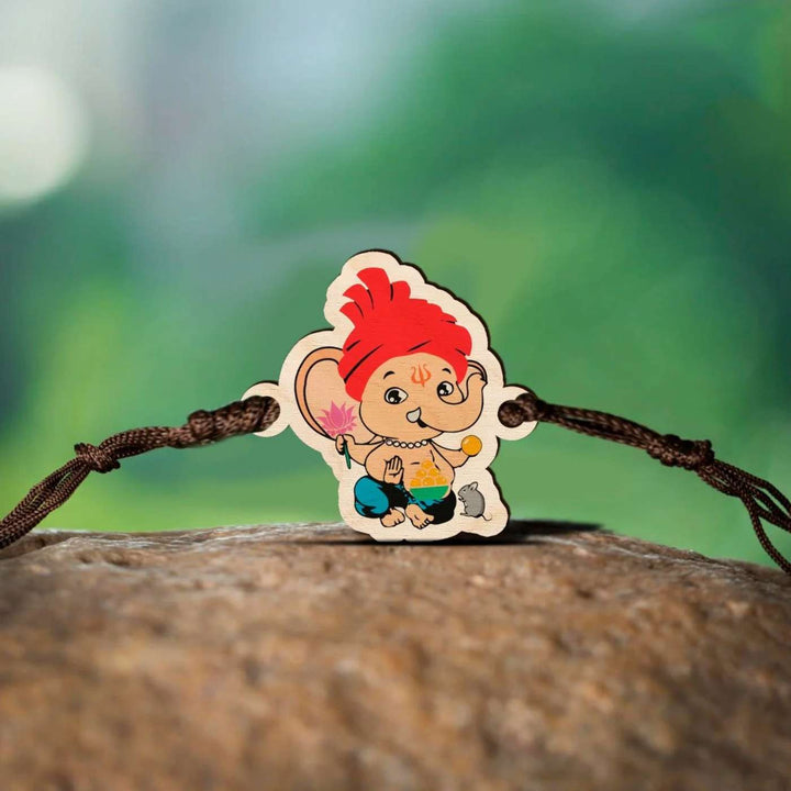 Handmade Ganapati Wooden Kids Rakhi With Roli Chawal - Rakhi laid on natural surface