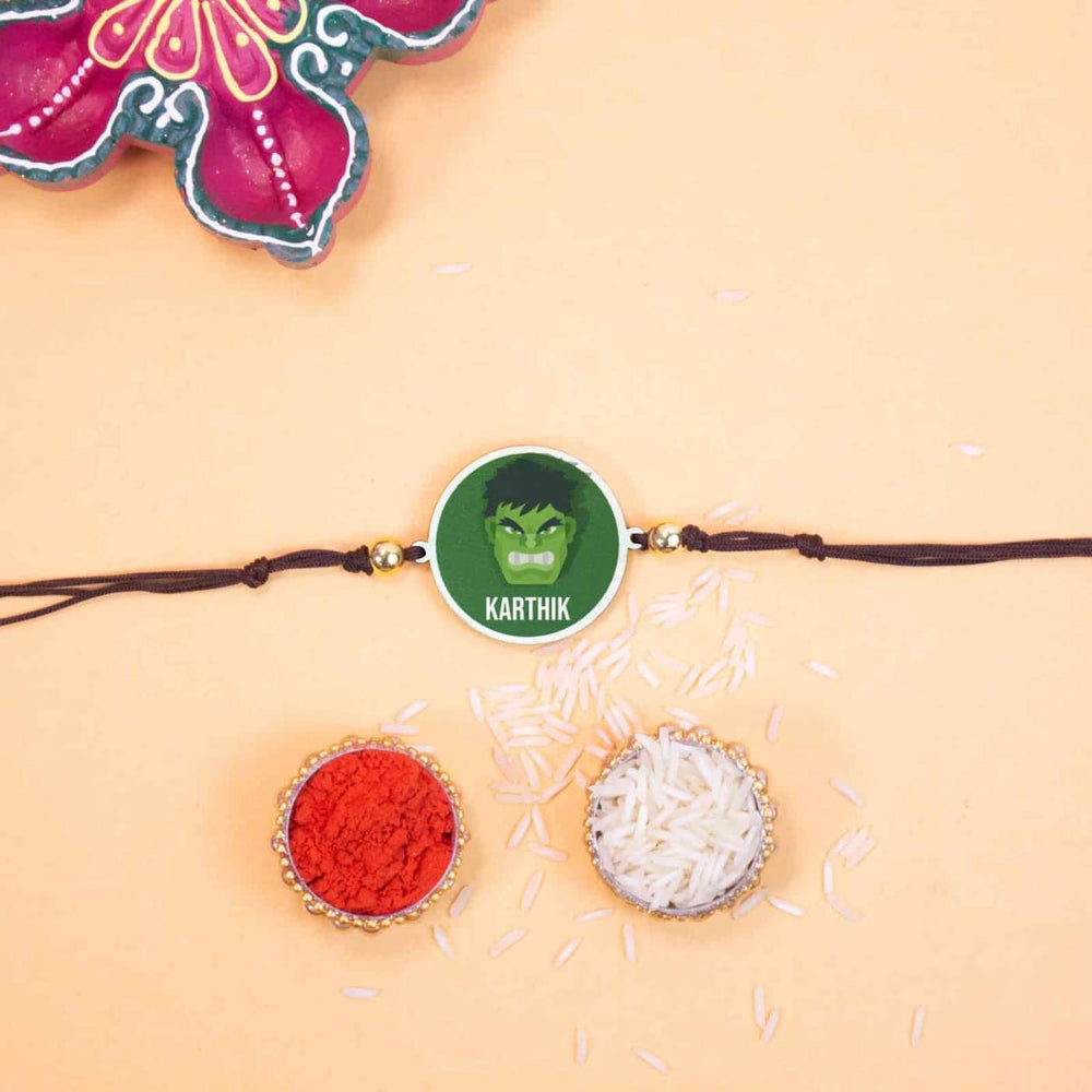 Personalized Handmade Hulk Wooden Kids Rakhi With Roli Chawal - Laid Flat with Ritual Items