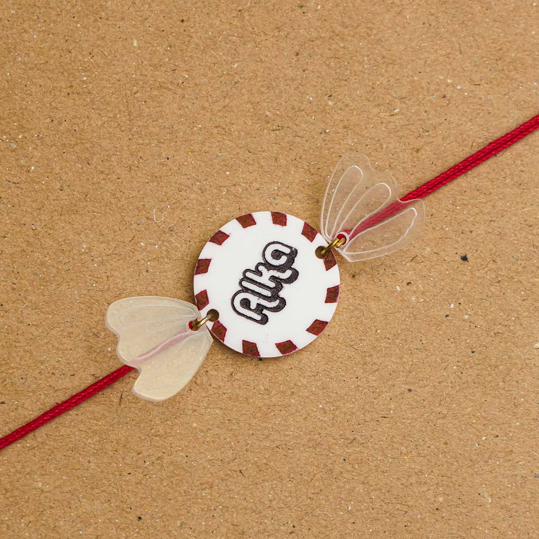 Personalized Handmade Chocolate Acrylic Kids Rakhi With Roli Chawal - Close-up on textured surface