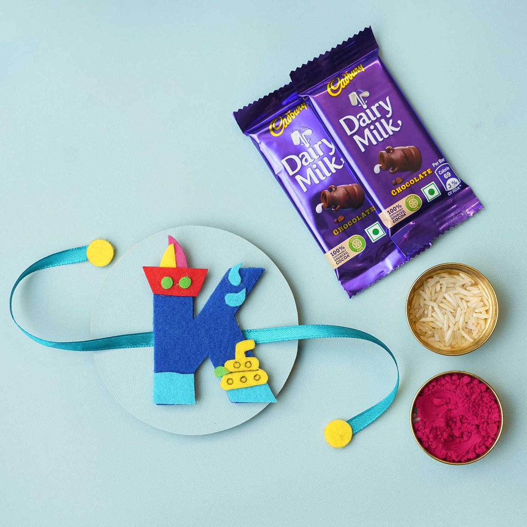 Personalised Handmade Boat Felt Rakhi With Chocolates Roli Chawal - Blue K Rakhi with Gifts Flat Lay