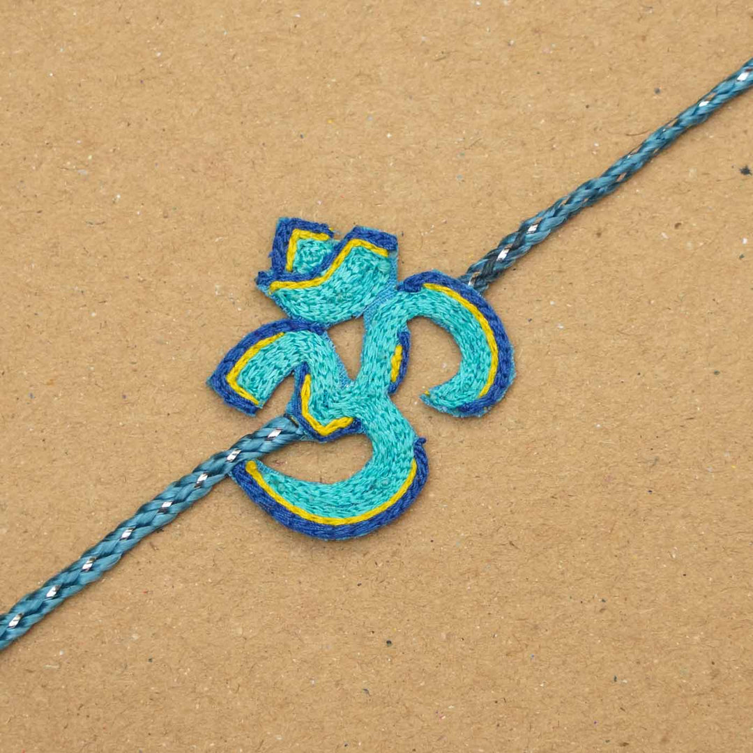 Handmade Beaded Om Rakhi With Roli Chawal - Close-up of blue Om rakhi