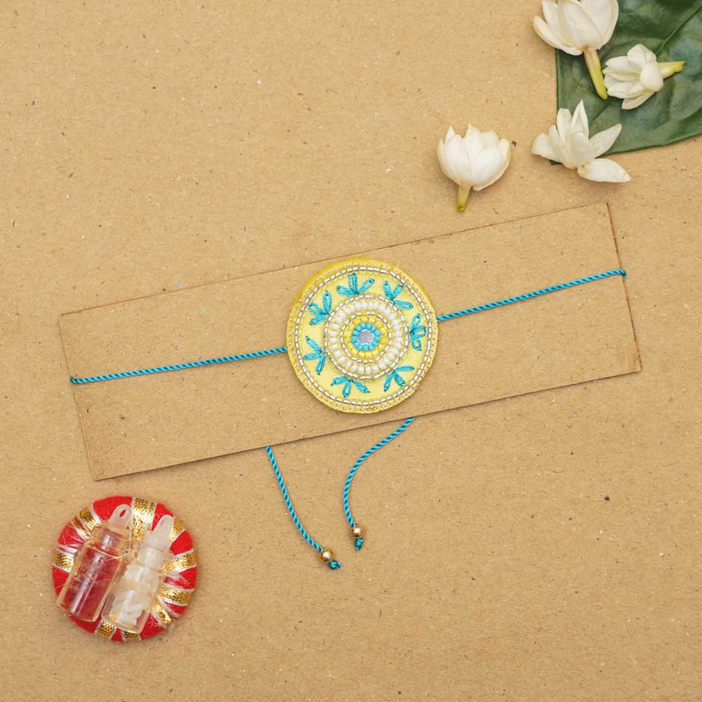 Handmade Beaded Round Rakhi With Roli Chawal - Flat lay with gift items
