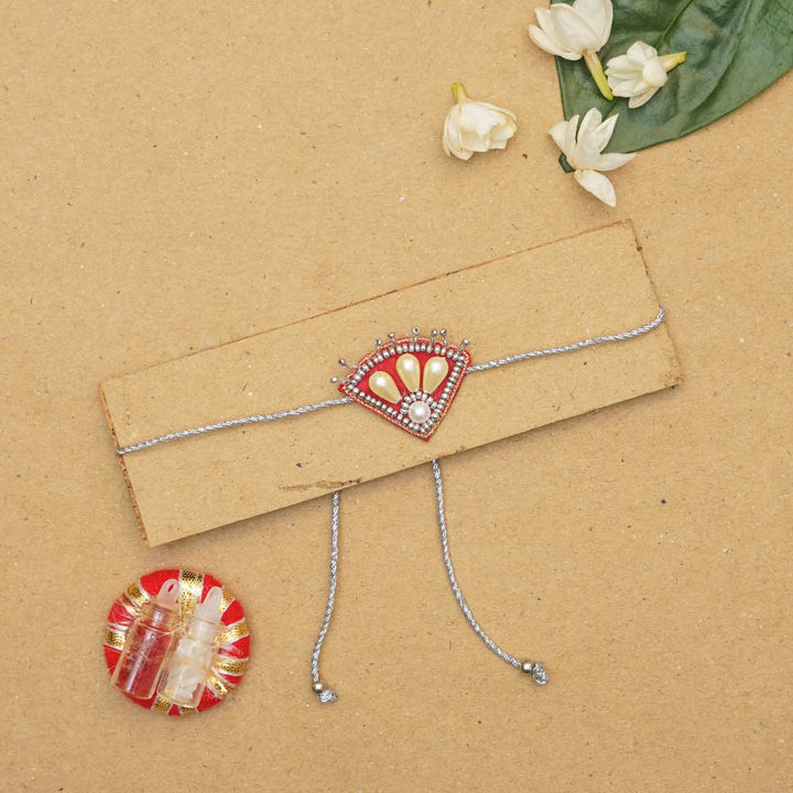 Handmade Beaded Paw Silver Rakhi With Roli Chawal - Rakhi on display card with accessories