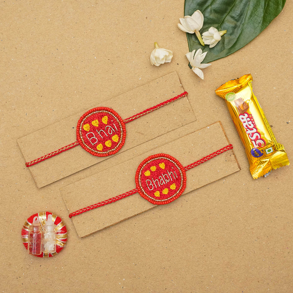 Handmade Beaded Rakhi Hamper For Bhaiya And Bhabhi Set Of 3 1 - Flat Lay with Rakhis and Chocolate