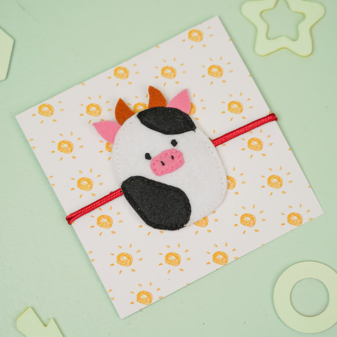 Handmade Squish Mallows Cow Theme Felt Kids Rakhi - Wrapped on Patterned Card, Angled View