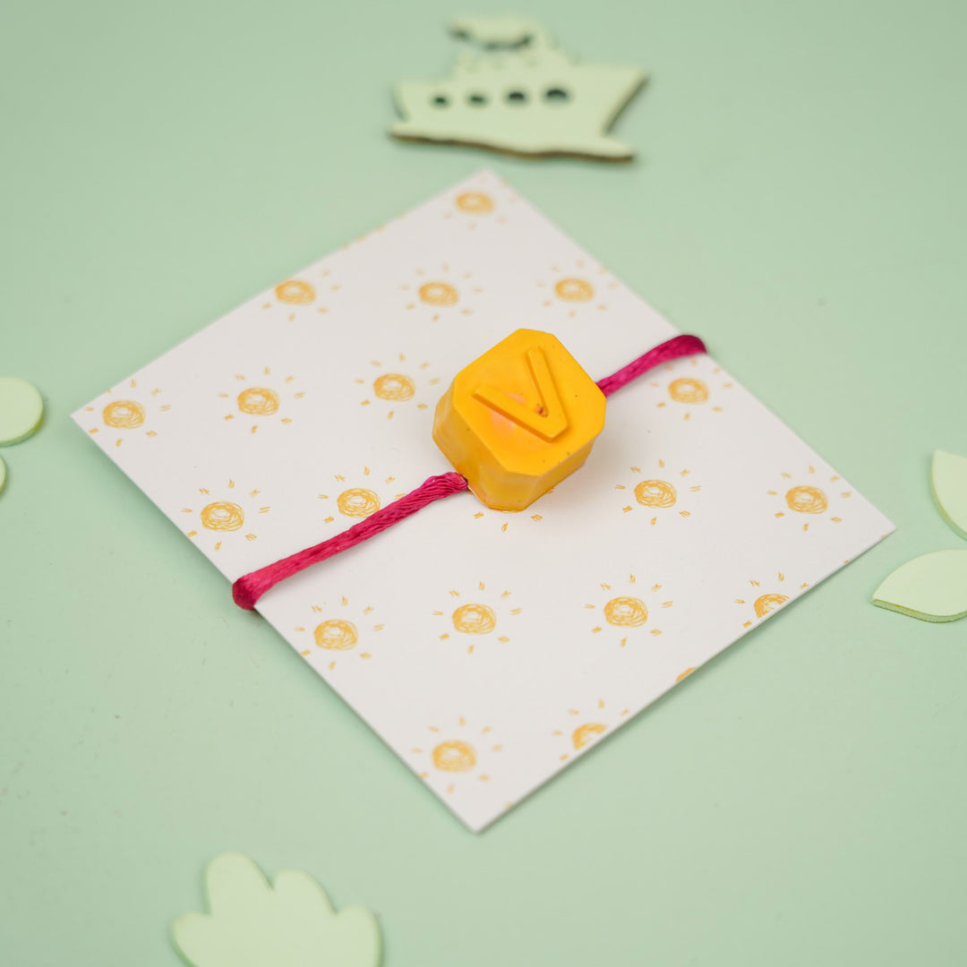 Personalized Handmade Mini Letters Wax Rakhi For Kids - Angled product view with "V" charm