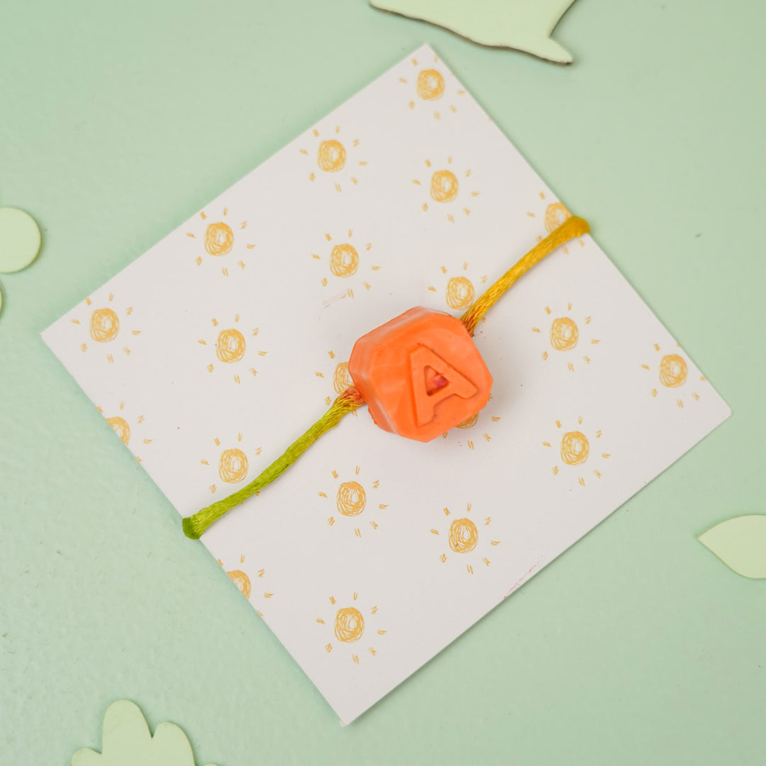 Personalized Handmade Mini Letters Wax Rakhi For Kids - Angled product view with "A" charm