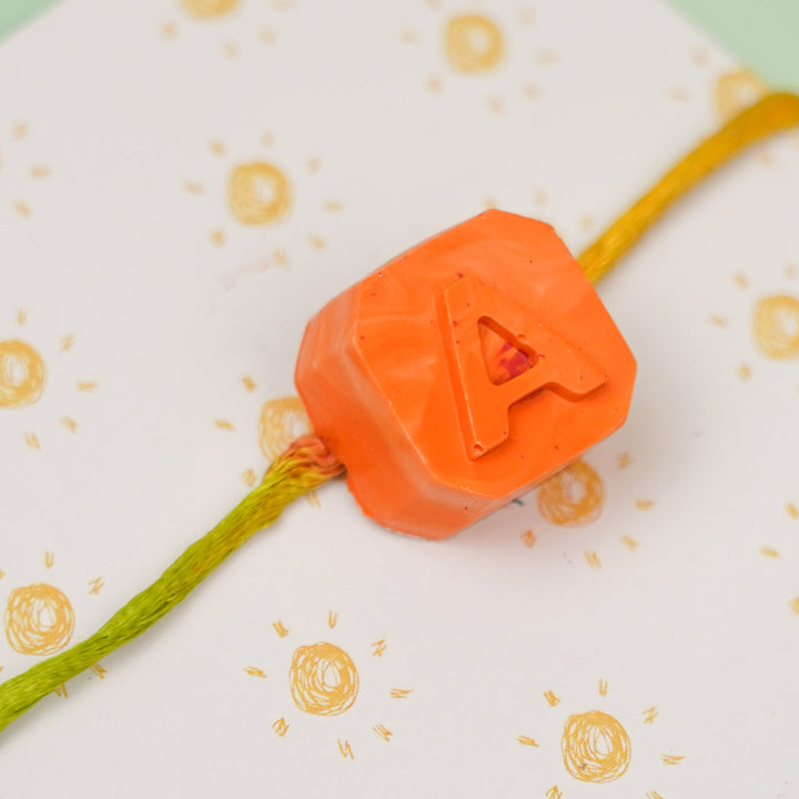 Personalized Handmade Mini Letters Wax Rakhi For Kids - Close-up of orange "A" charm