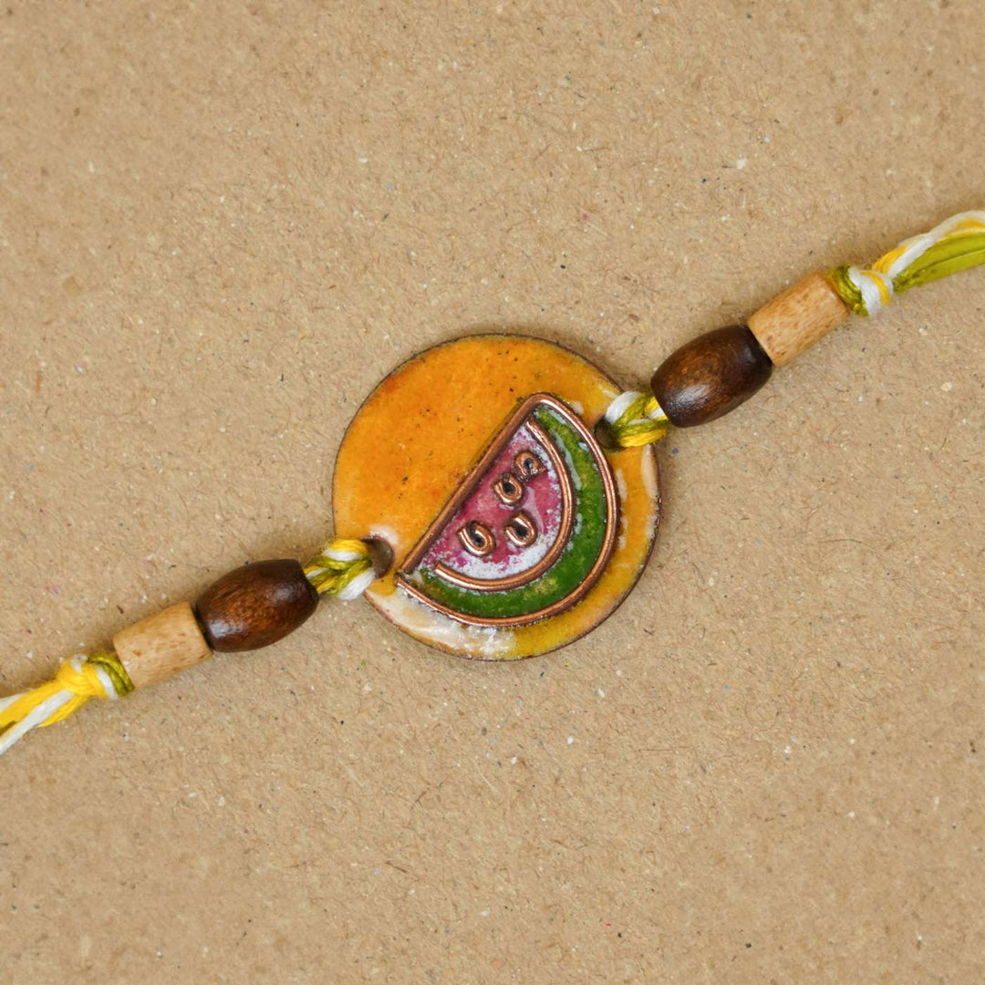 Handmade Tarbooz Red Copper Enamel Rakhi With Chocolates And Roli Chawal - Close-up of Rakhi centerpiece