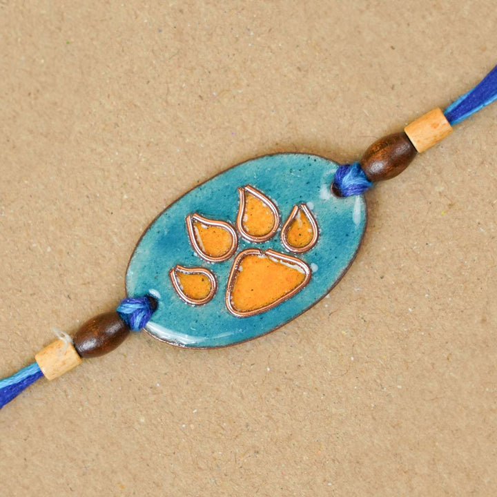 Handmade Pawfect Copper Enamel Rakhi With Chocolates And Roli Chawal - Close-up of Orange Paw Charm