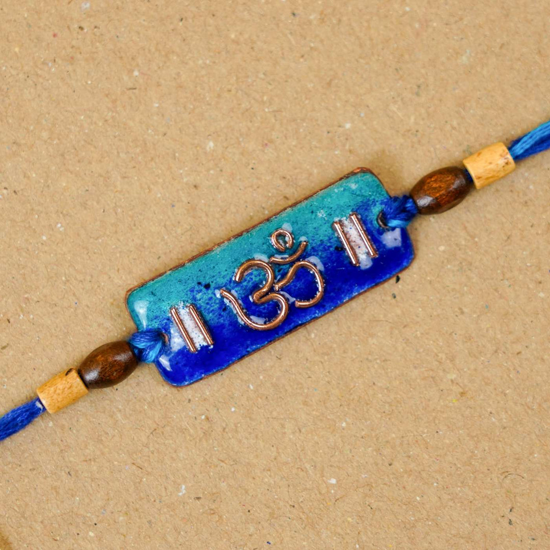 Handmade Rectangle Om Copper Enamel Rakhi With Chocolates And Roli Chawal - Top View Close-up (2)