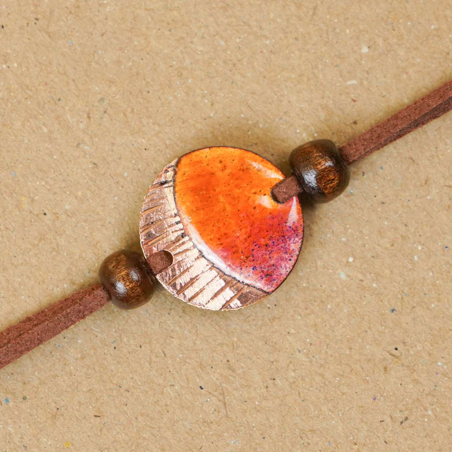 Handmade Ambar Textured Yellow Copper Enamel Rakhi With Chocolates And Roli Chawal - Close-up of Bracelet Pendant