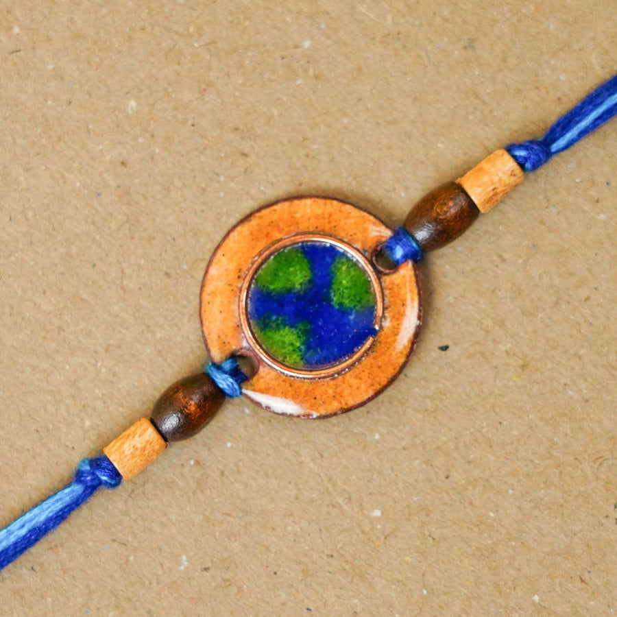 Handmade Earthy Brown Copper Enamel Rakhi With Chocolates And Roli Chawal - Close-up of planet centerpiece