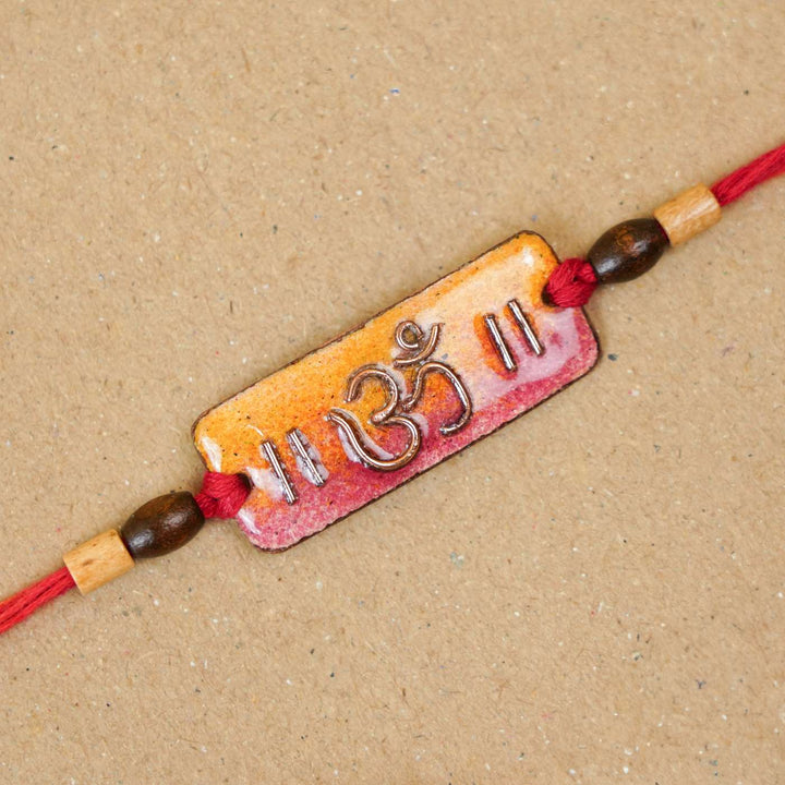 Handmade Rectangle Om Copper Enamel Rakhi With Chocolates And Roli Chawal - Top View Close-up