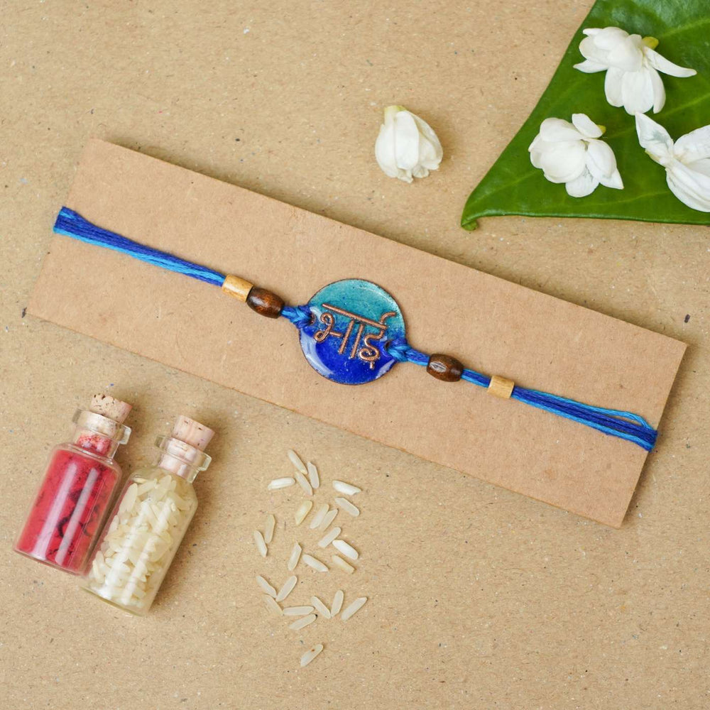 Handmade Bhai Blue Copper Enamel Rakhi With Chocolates And Roli Chawal - Packaged Rakhi with decorative elements