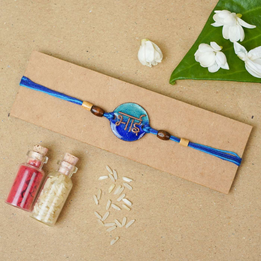 Handmade Bhai Blue Copper Enamel Rakhi With Chocolates And Roli Chawal - Packaged Rakhi with decorative elements