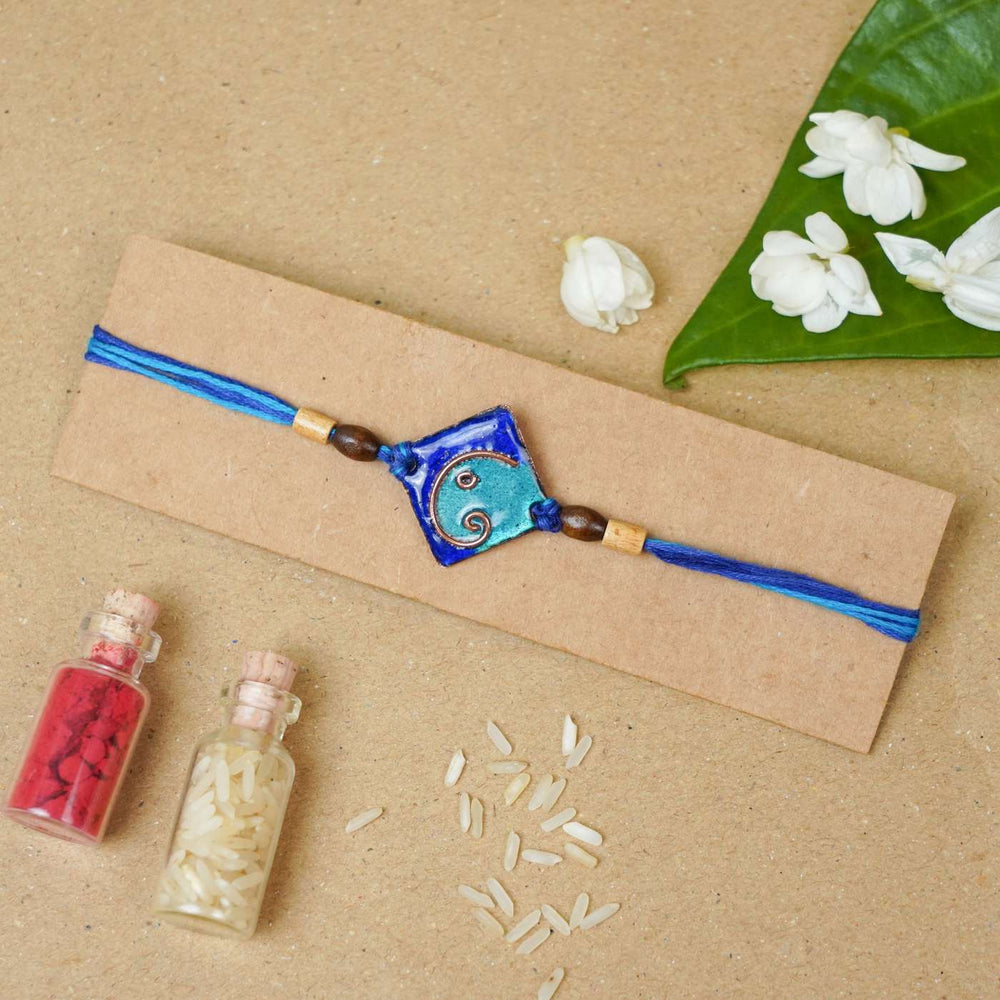 Handmade Geometric Ganesha Blue Copper Enamel Rakhi With Chocolates And Roli Chawal - Rakhi on kraft card display