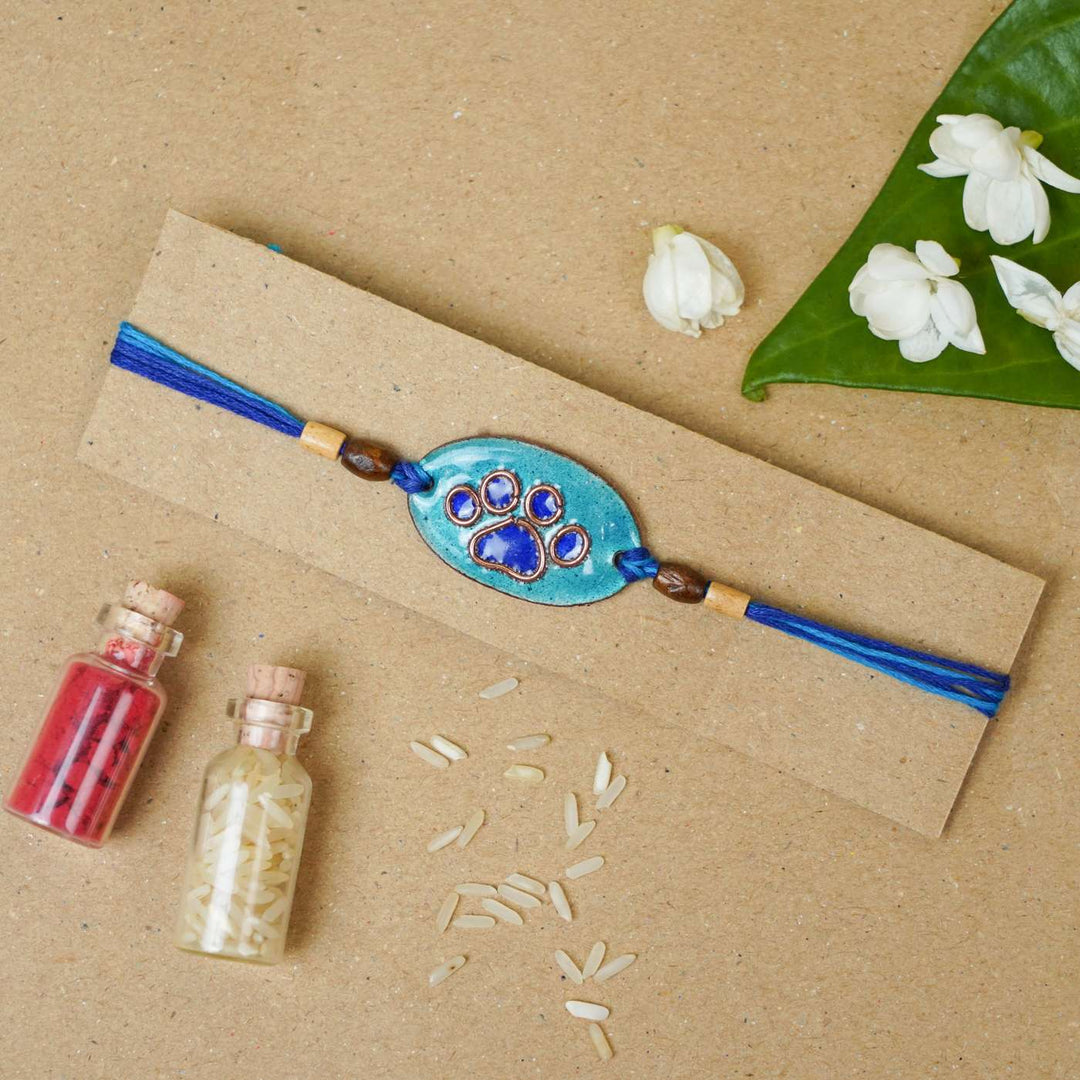Handmade Pawfect Copper Enamel Rakhi With Chocolates And Roli Chawal - Blue Paw Charm on Card