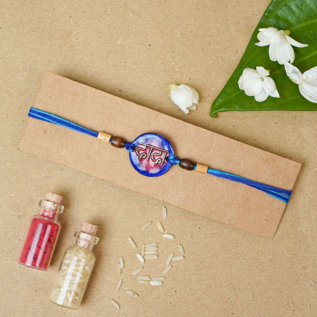 Handmade Dada Blue Copper Enamel Rakhi With Chocolates And Roli Chawal - Rakhi on packaging with decor