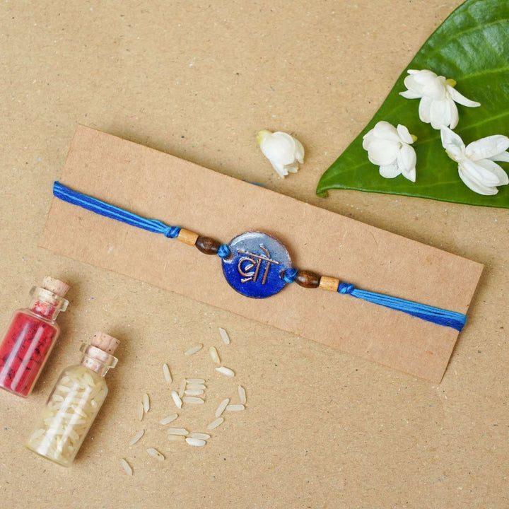 Handmade Bro Blue Copper Enamel Rakhi With Chocolates And Roli Chawal - Packaged Rakhi with decorative elements