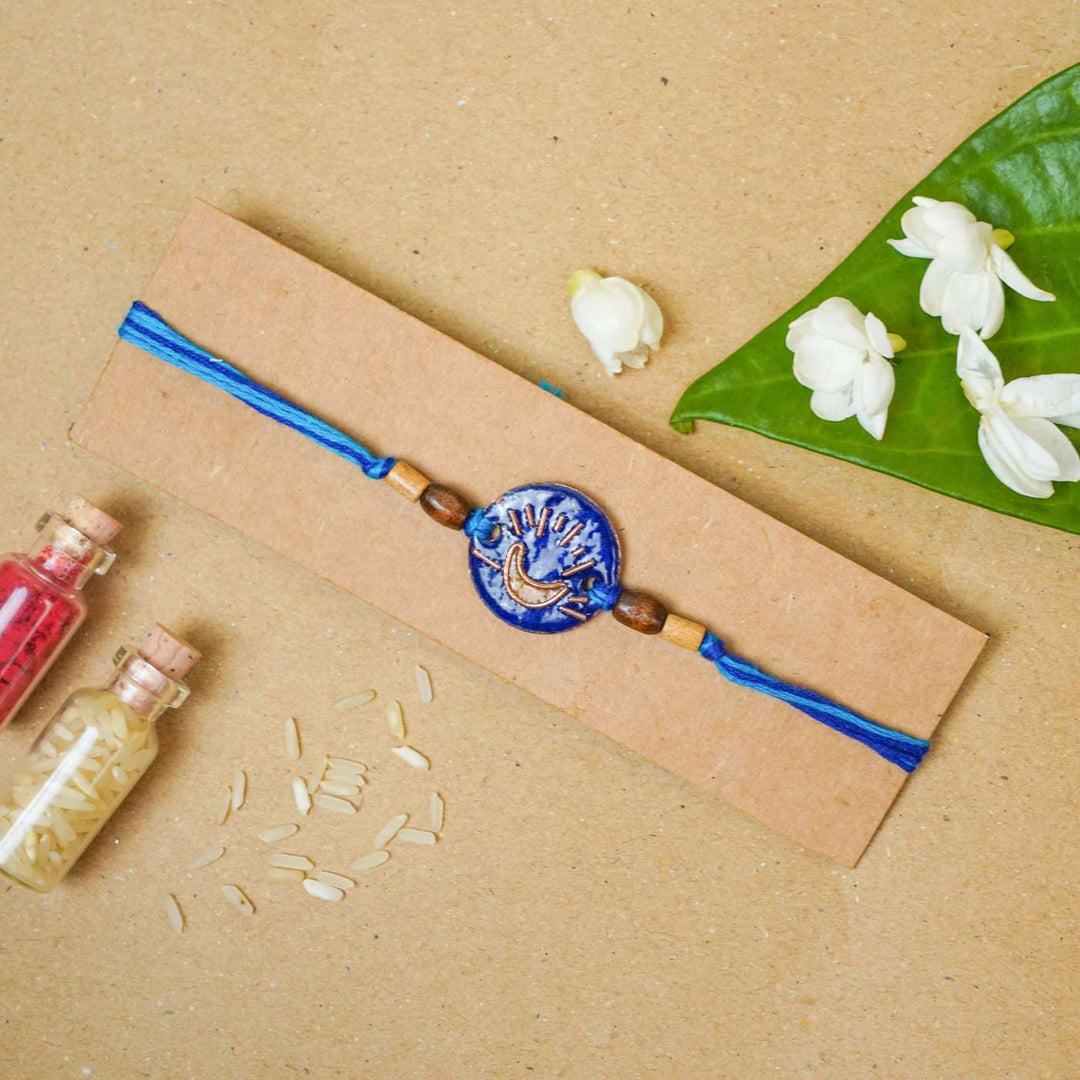 Handmade Chanda Blue Copper Enamel Rakhi With Chocolates And Roli Chawal - Flat Lay with Flowers and Decor