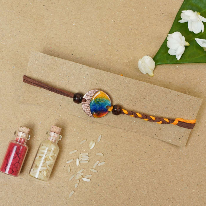 Handmade Indraa Textured Multicolour Copper Enamel Rakhi With Chocolates And Roli Chawal - Flat lay with decorative props