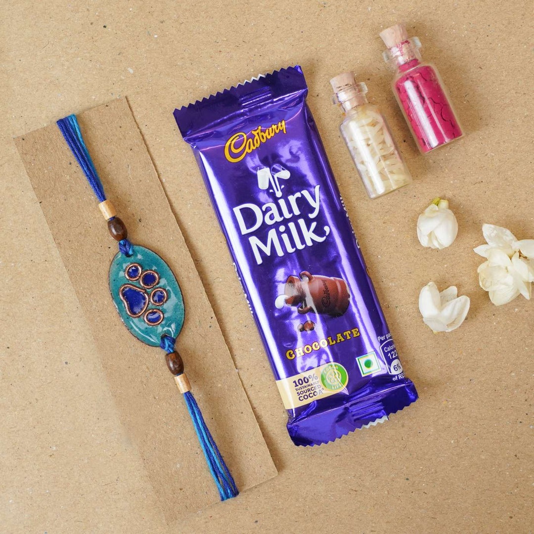 Handmade Pawfect Copper Enamel Rakhi With Chocolates And Roli Chawal - Blue Paw Charm with Gifts
