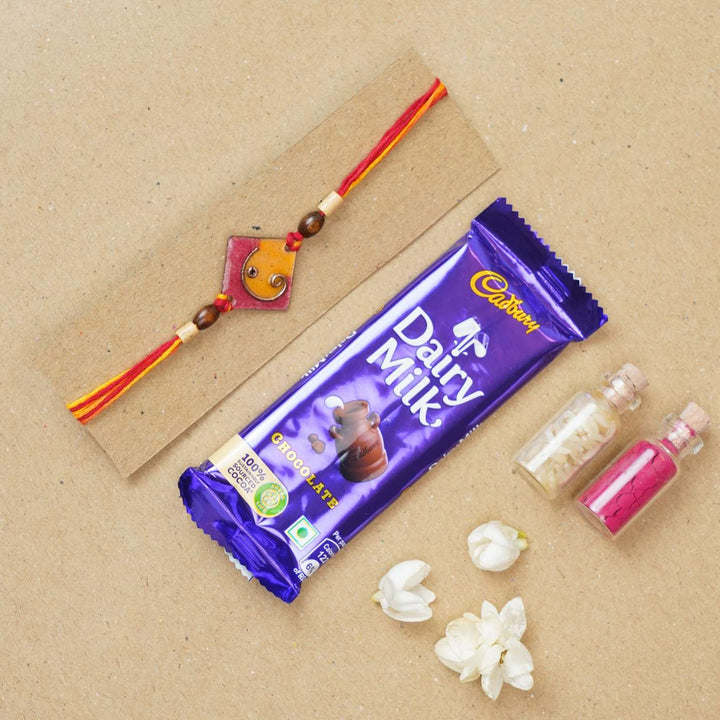 Handmade Square Ganesh Copper Enamel Rakhi With Chocolates And Roli Chawal - Orange rakhi with chocolate and accessories