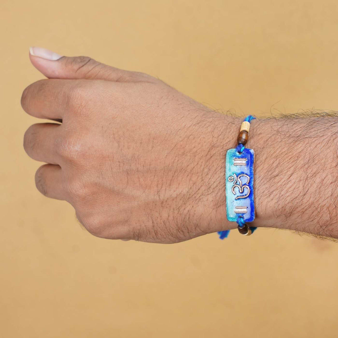 Handmade Rectangle Om Copper Enamel Rakhi With Chocolates And Roli Chawal - On Wrist Model Display (8)