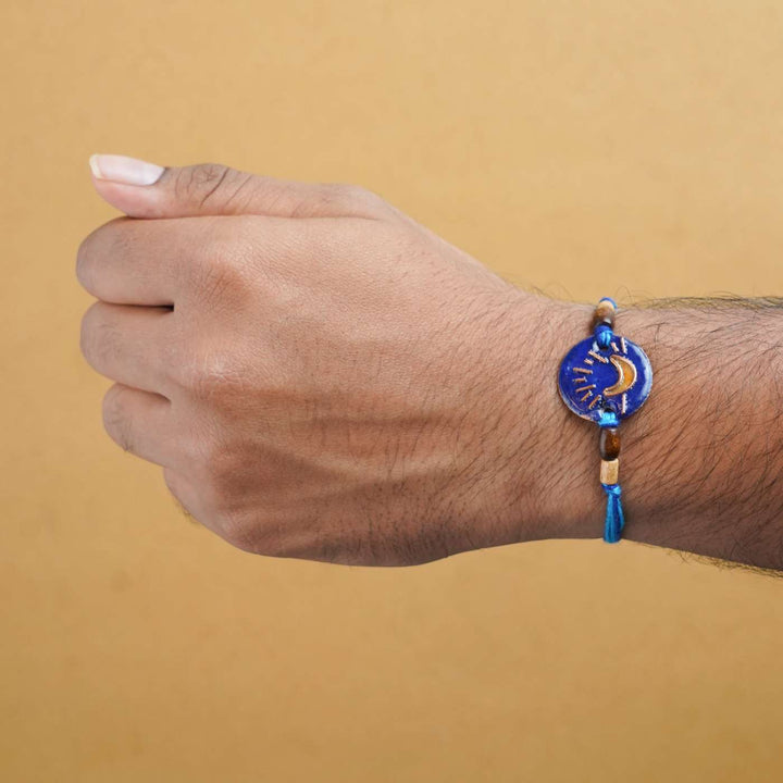 Handmade Chanda Blue Copper Enamel Rakhi With Chocolates And Roli Chawal - Worn on Wrist Showing Fit