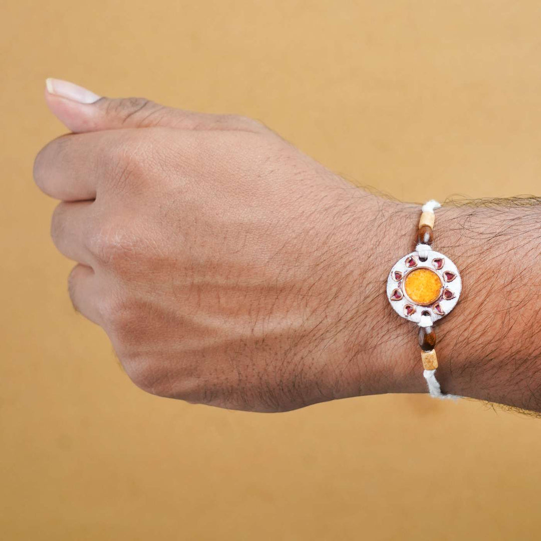 Handmade Sooraj White Copper Enamel Rakhi With Chocolates And Roli Chawal - Rakhi worn on wrist