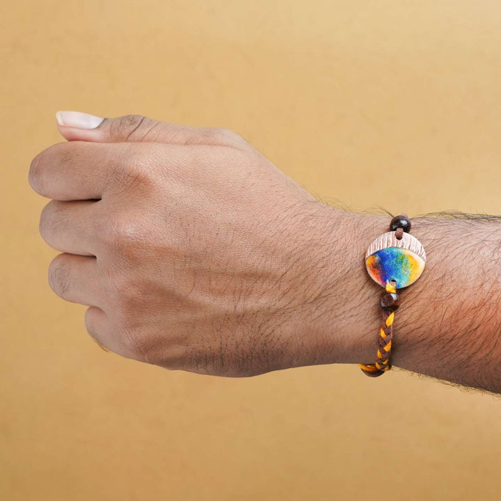 Handmade Indraa Textured Multicolour Copper Enamel Rakhi With Chocolates And Roli Chawal - Worn on wrist display