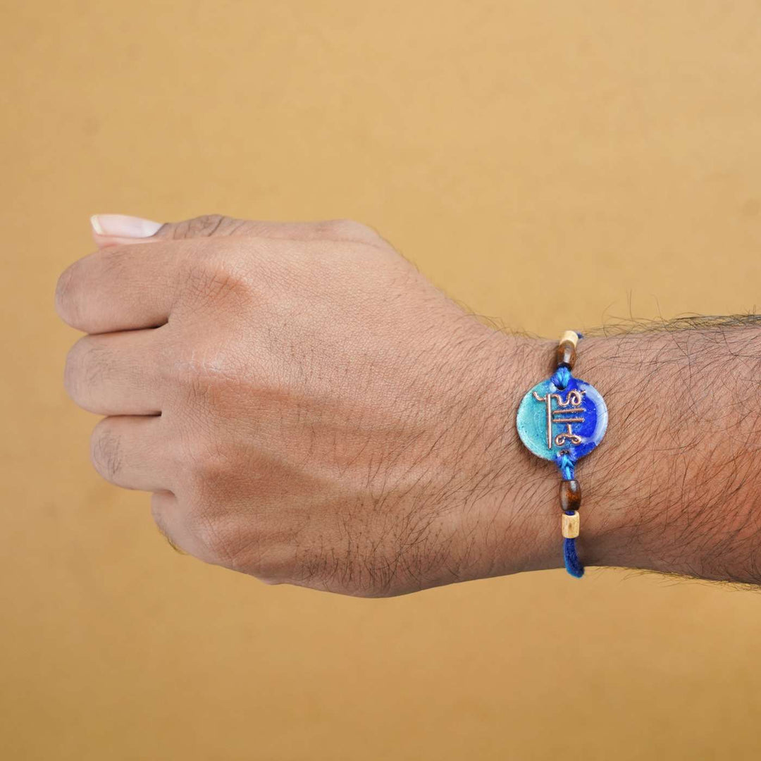 Handmade Bhai Blue Copper Enamel Rakhi With Chocolates And Roli Chawal - Worn Rakhi on wrist
